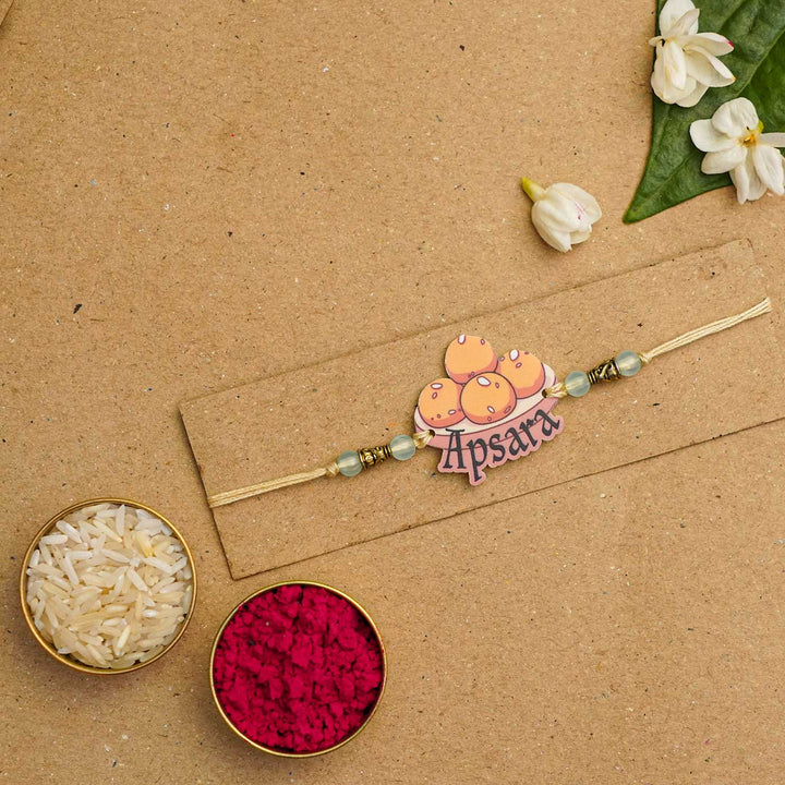 Personalized Handmade Laddu Acrylic Kids Rakhi With Roli Chawal - Displayed on cardboard packaging
