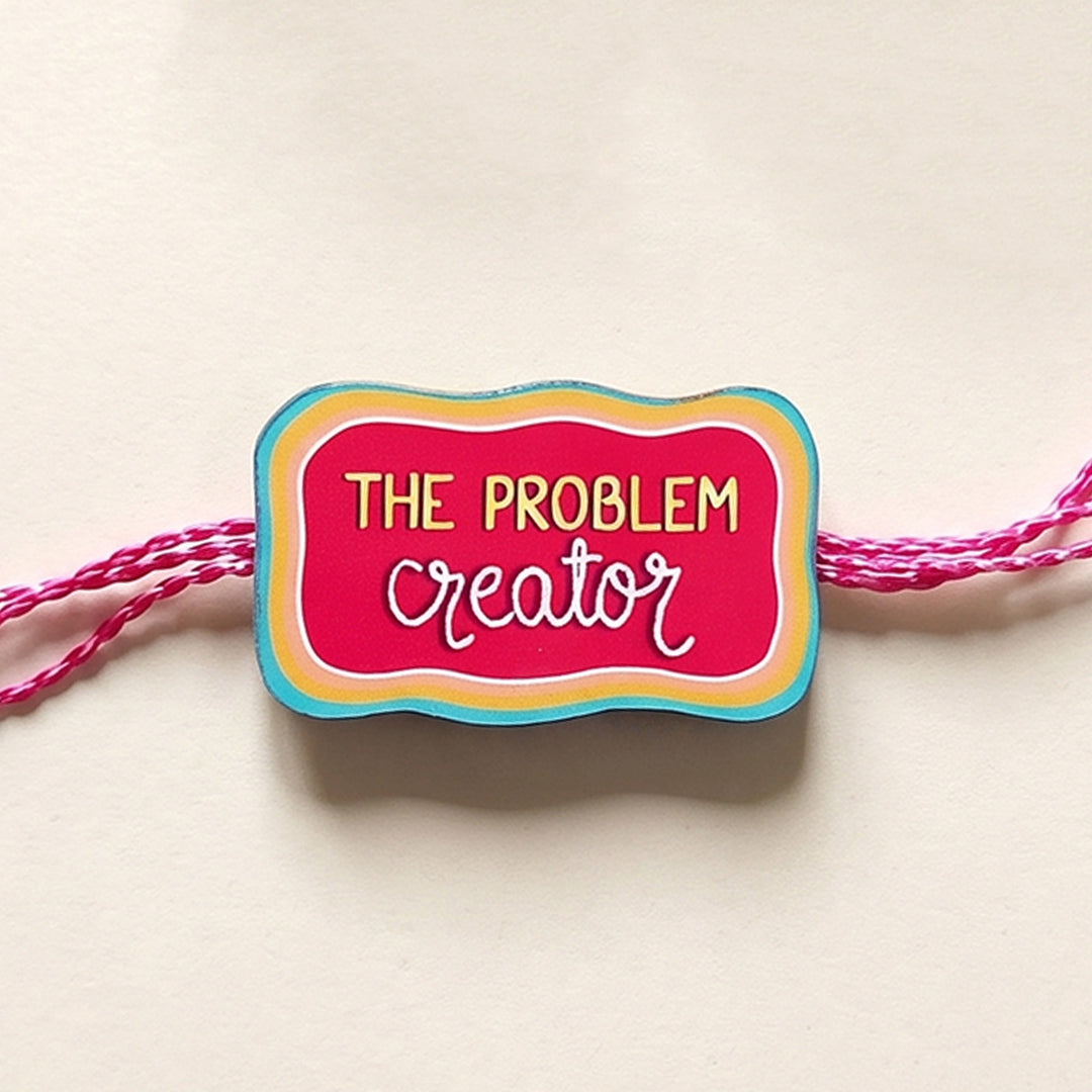 Glossy Printed Wooden 'Problem Creator' Rakhi With Kumkum Rice For Brother