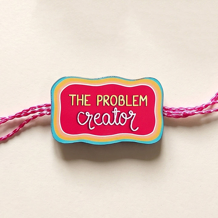 Glossy Printed Wooden 'Problem Creator' Rakhi With Kumkum Rice For Brother