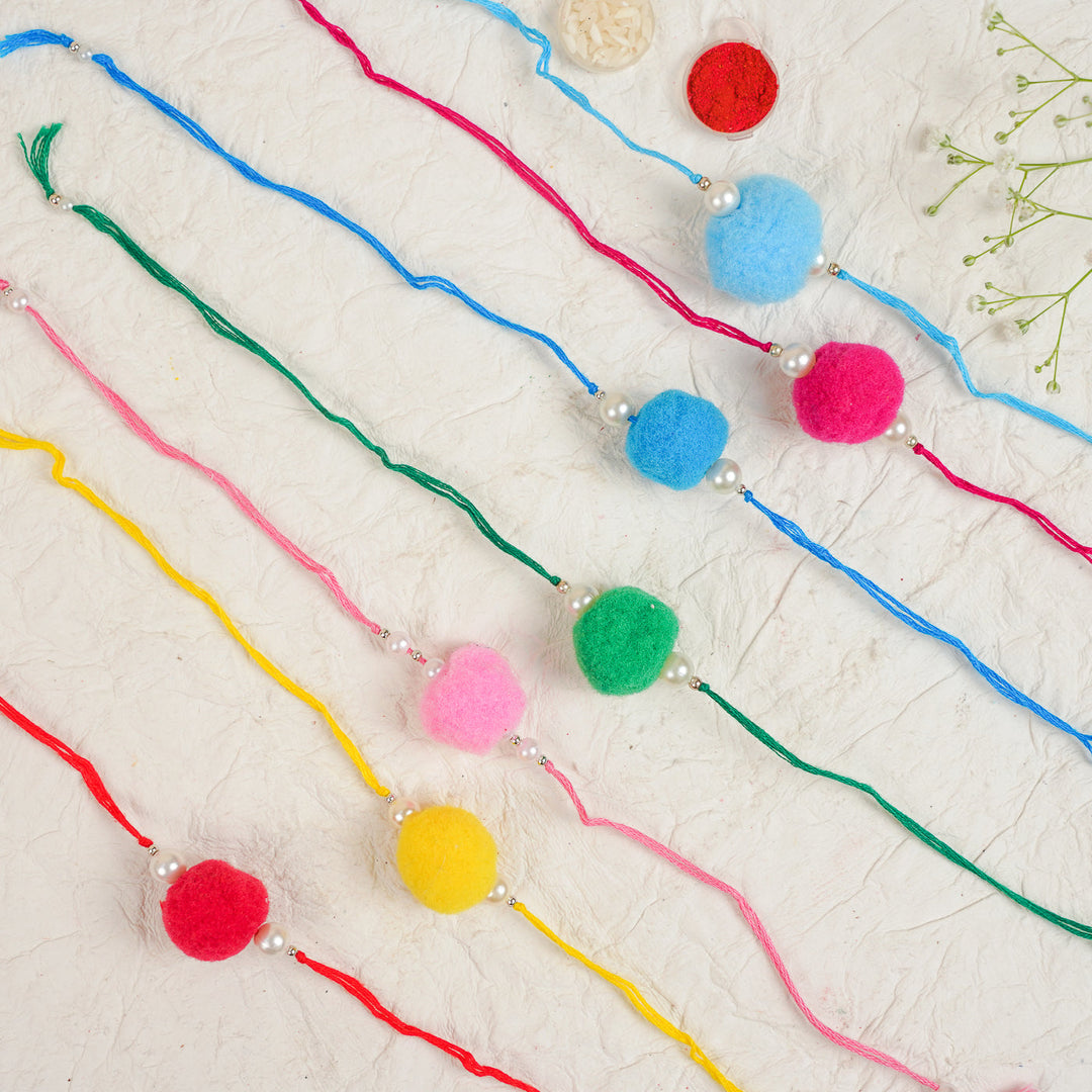 Handmade Pompom Rakhi With Roli Chawal Set Of 12 - Flat Lay of Multiple Rakhis