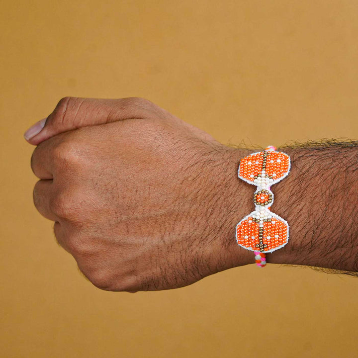 Reusable Beaded Orange Bug Rakhi With Roli Chawal - On wrist showing fit and design