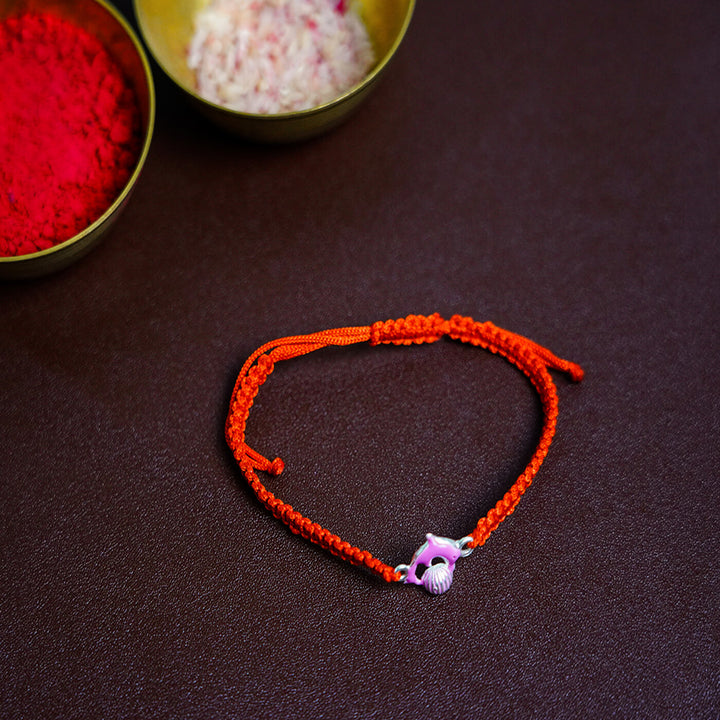 Handcrafted Silver Motif Adjustable Rakhi For Kids With Rice Roli 3 - Laid Flat with Ritual Items