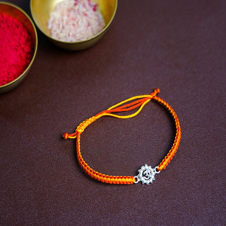 Handcrafted Silver Motif Adjustable Rakhi With Rice Roli 2 - Flat Lay with Decorative Bowls