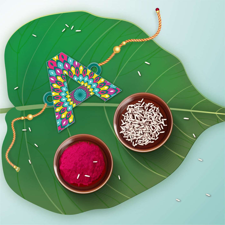 Personalized Handmade Printed Alphabet Wooden Rudraksha Rakhi With Roli Chawal - Styled on Green Leaf