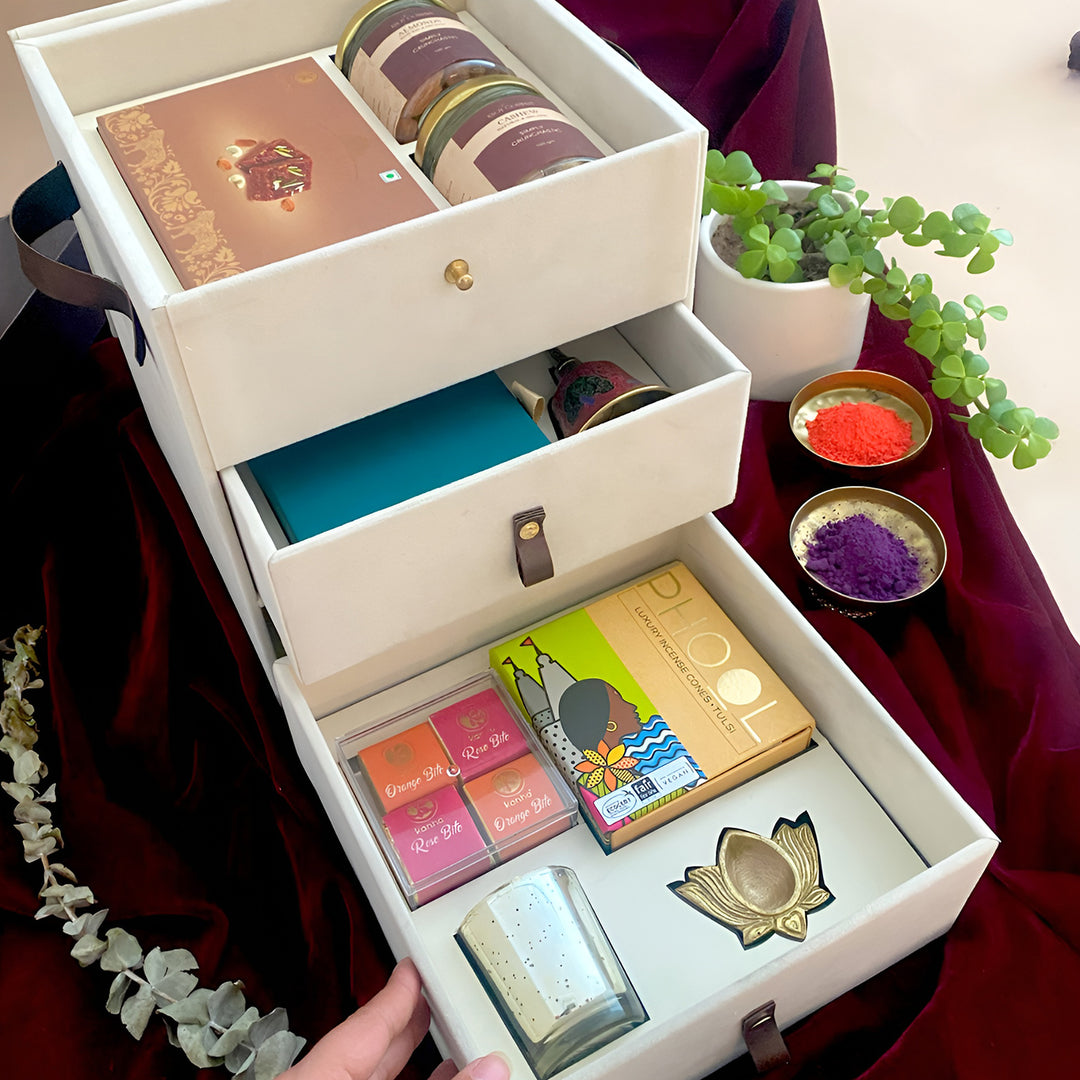The Ivory Glow Diwali Gift Hamper | Includes 1 Doda Barfi, 2 Dry Fruit Jars, 1 Pooja Bell, 1 Pooja Samagri, 4 Assorted Bites, 1 Incense Cones Pack, 1 Brass Diya, 1 Candle, 1 Gift Box