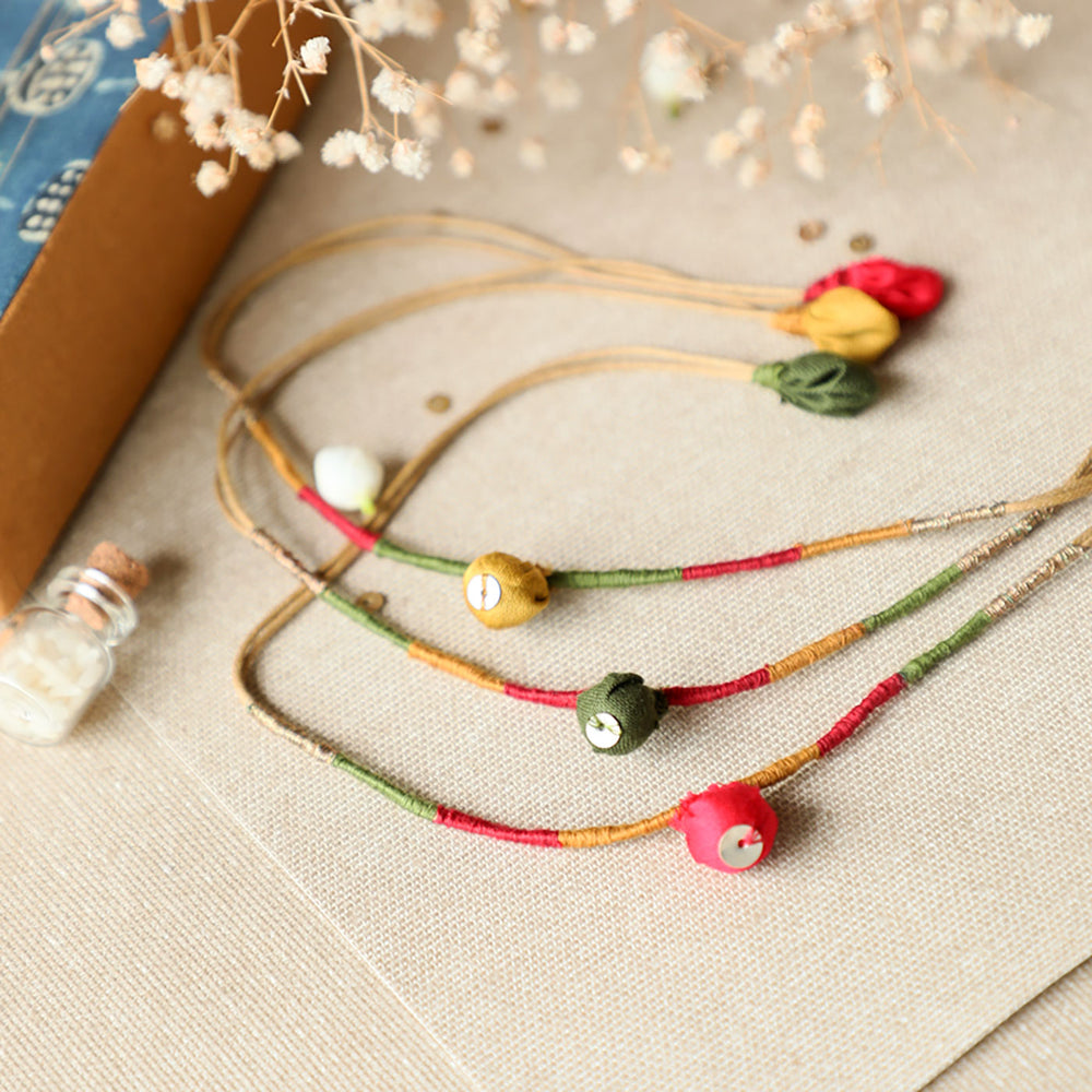 Handmade Reusable Colorful Pods Upcycled Fabric Rakhi With Roli Chawal For Brother Set Of 3 - Flat lay of necklace strings