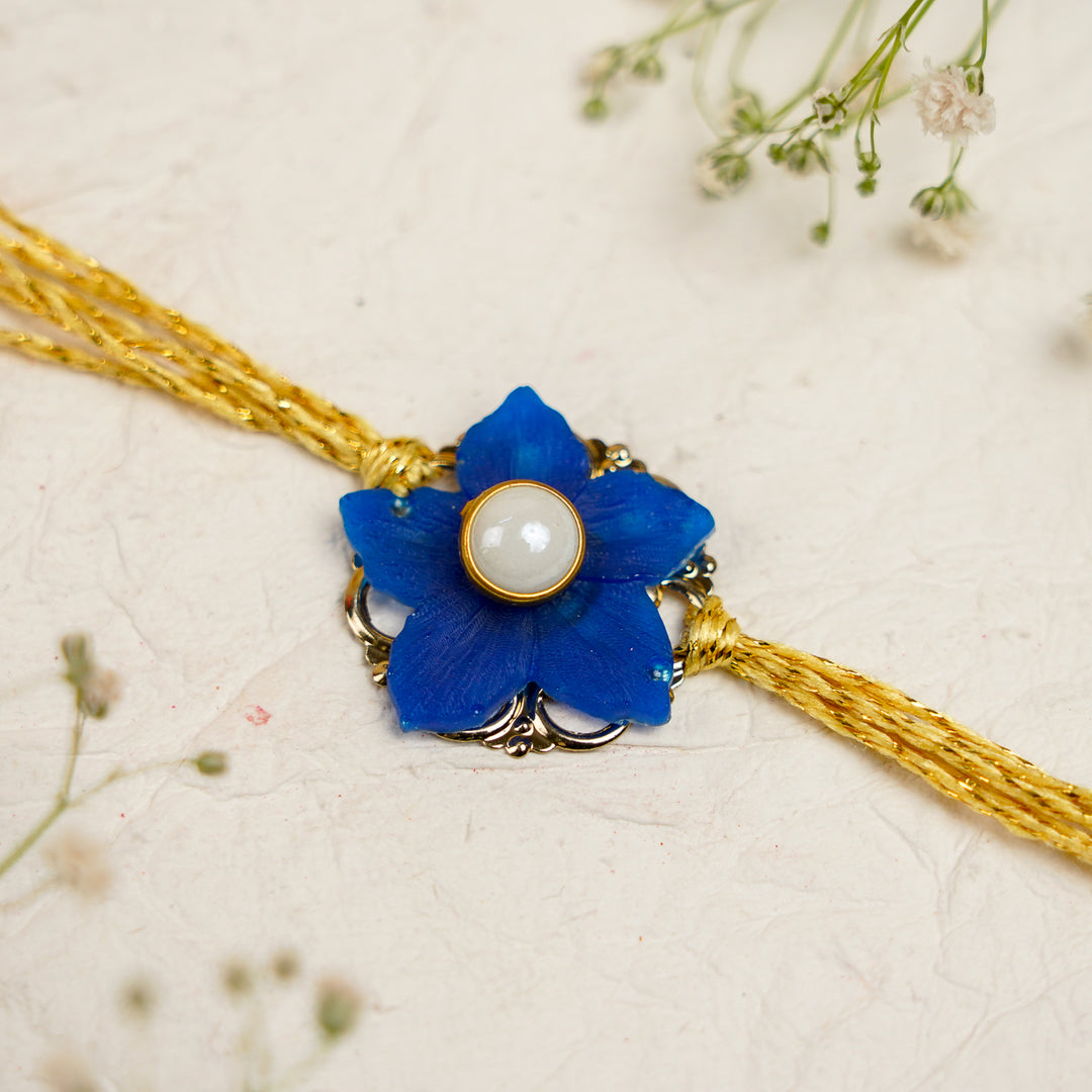 Blue White Pearls And Zari Resin Bracelet Rakhi With Roli Chawal For Bhaiya And Bhabhi - Close-up of Blue Flower Rakhi