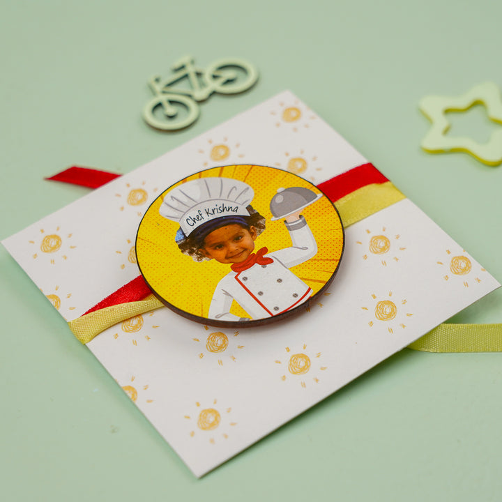 Photo Personalized Handmade Reusable Caricature Little Chef Mdf Wood Kids Rakhi With Roli Chawal - Angled view of badge on card