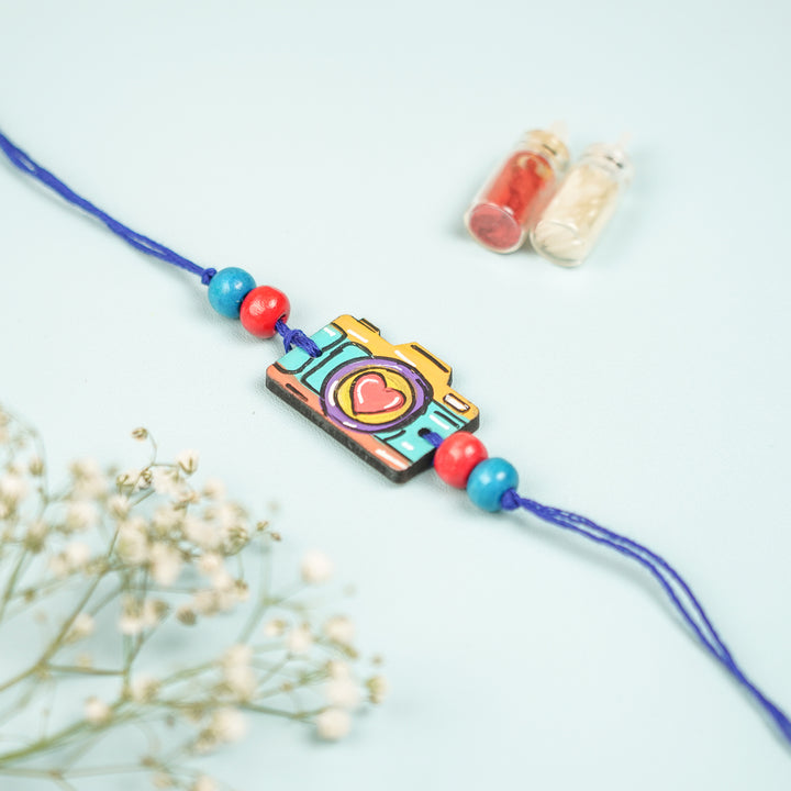 Customized Hand Painted Camera Design Mdf Wood Rakhi - Close-up Front View with Decoration