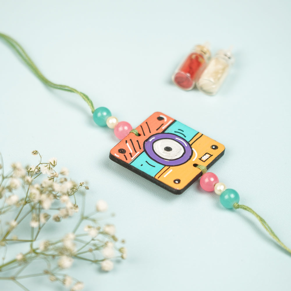 Customized Hand Painted Camera Design Mdf Wood Rakhi - Close-up Front View with Decoration (2)