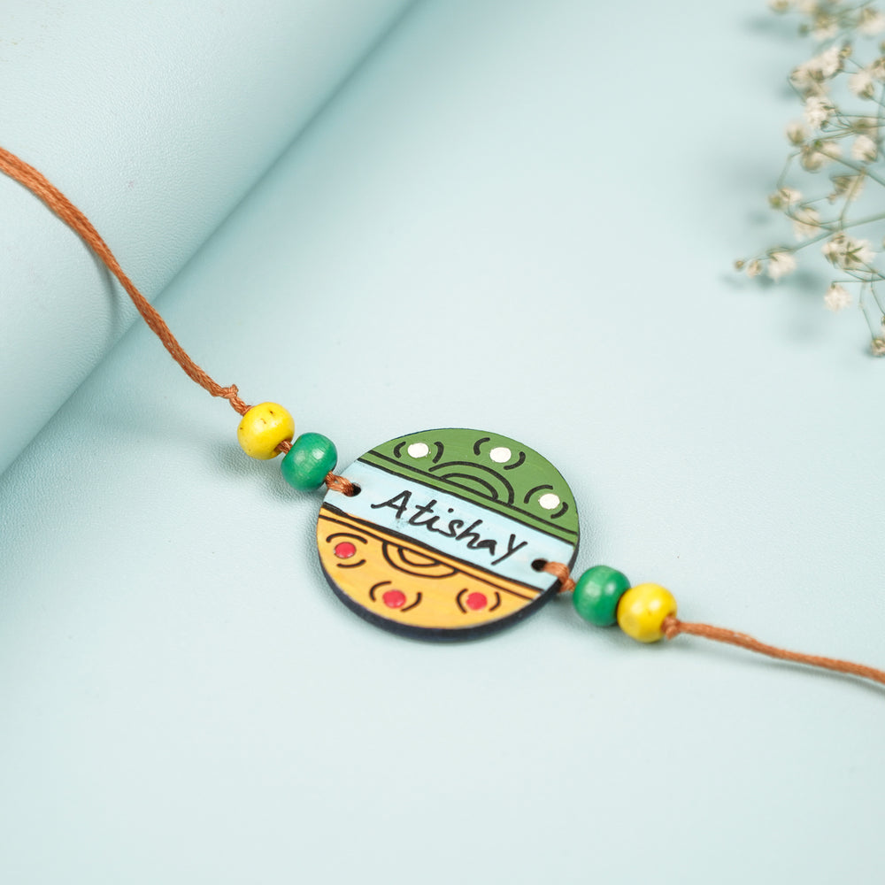 Personalized Hand Painted Round Design Mdf Wood Rakhi - Flat Lay Highlighting Central Pendant
