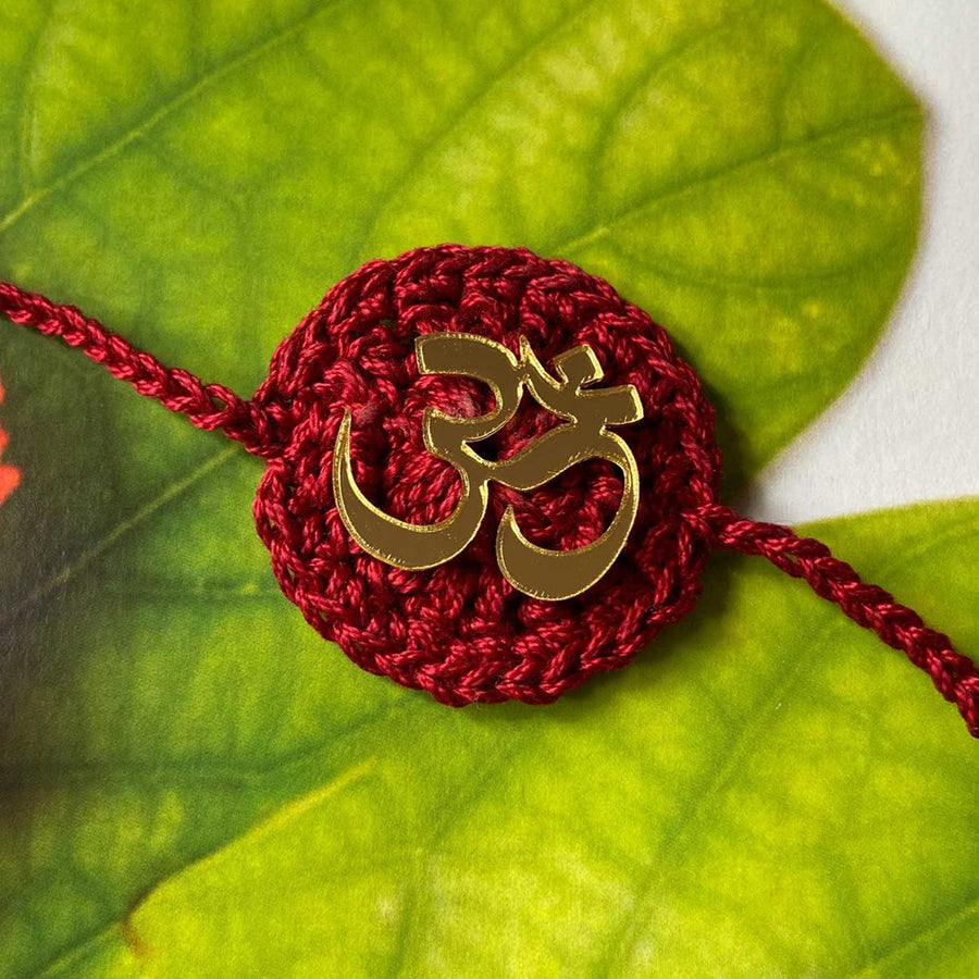 Handmade Crochet Religious Om Theme Cotton Rakhi With Roli Chawal - Close-up with Leaf Background