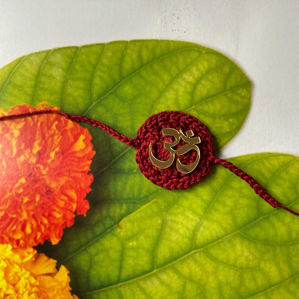 Handmade Crochet Religious Om Theme Cotton Rakhi With Roli Chawal - Top View with Flower and Leaves Background