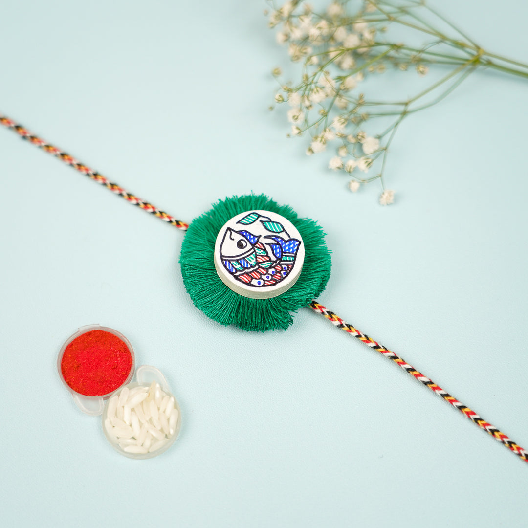 Hand Painted Madhubani Green Fish Design Wooden Rakhi With Roli Chawal For Brother - Top View with Accessories
