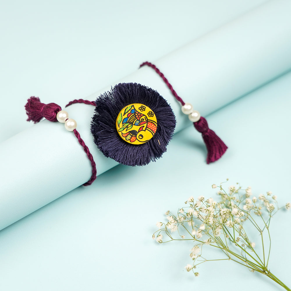 Hand Painted Madhubani Black Peacock Design Wooden Rakhi With Roli Chawal For Brother - Rolled Display with Floral Accent