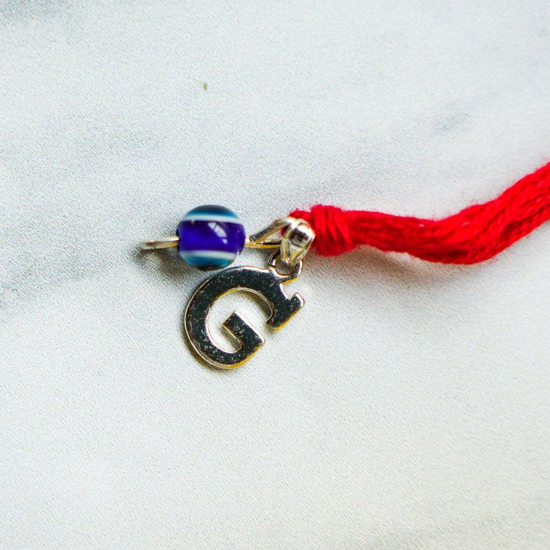 Handcrafted Silver Ganesha Rakhi With Rice Roli - Close-up of Charm and Bead