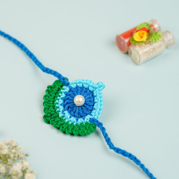 Handmade Crochet Peacock Feather Theme Rakhi With Roli Chawal - Close-up with decorative jars