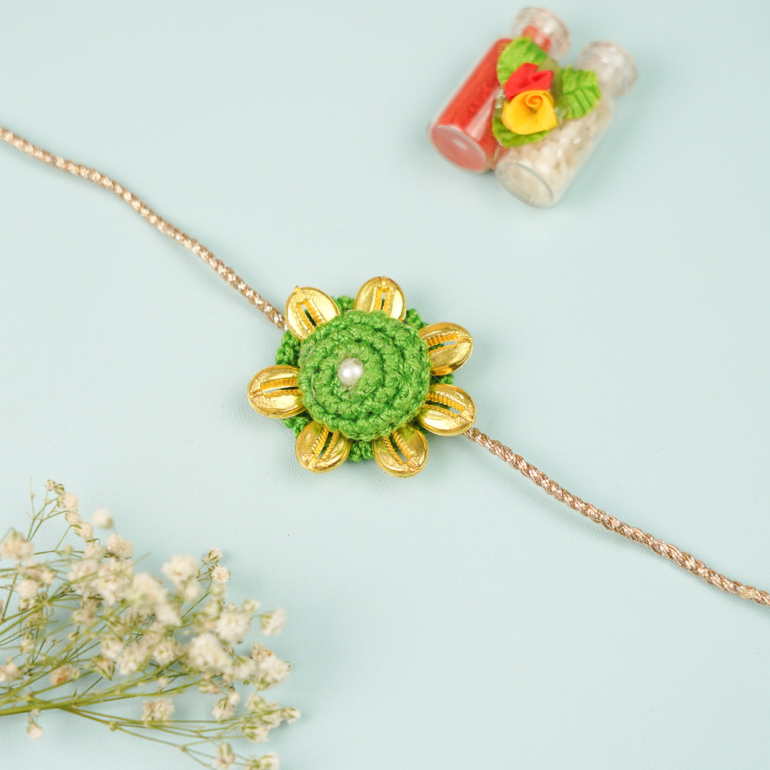 Handmade Crochet Cowry Beaded Floral Rakhi With Roli Chawal - Front View with Flowers and Bottles