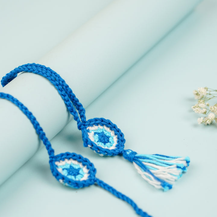 Handmade Crochet Evil Eye Bhaiya Bhabhi Rakhi With Roli Chawal Set Of 2 - Bracelet pair displayed on cylinder
