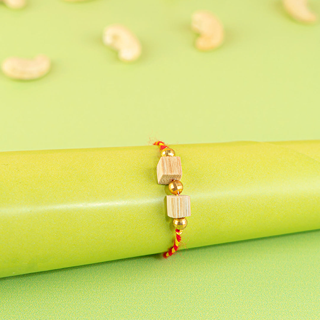 Ecofriendly Two Square Beads Bamboo Rakhi With Roli Chawal - Bracelet wrapped on green cylinder
