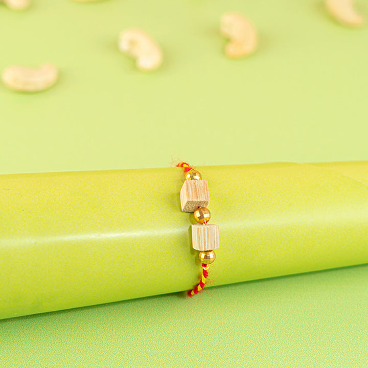 Ecofriendly Two Square Beads Bamboo Rakhi With Roli Chawal - Bracelet wrapped on green cylinder
