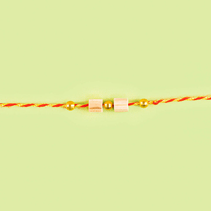 Ecofriendly Two Square Beads Bamboo Rakhi With Roli Chawal - Full bracelet view on flat surface