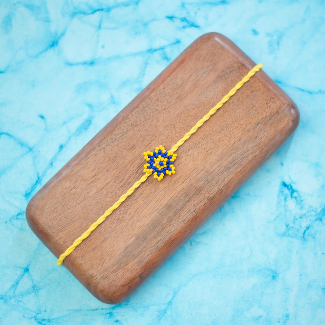Sitara Collection Glass Beeds Rakhi Yellow Blue - Flat Lay Front View on Wooden Box