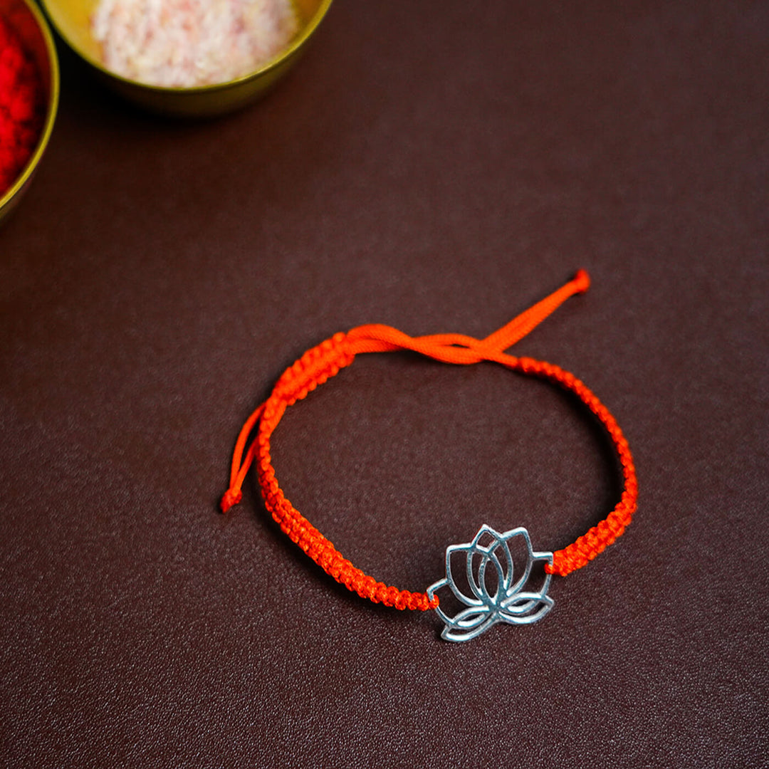 Handcrafted Silver Motif Adjustable Rakhi With Rice Roli 2 - Flat Lay with Lotus Pendant