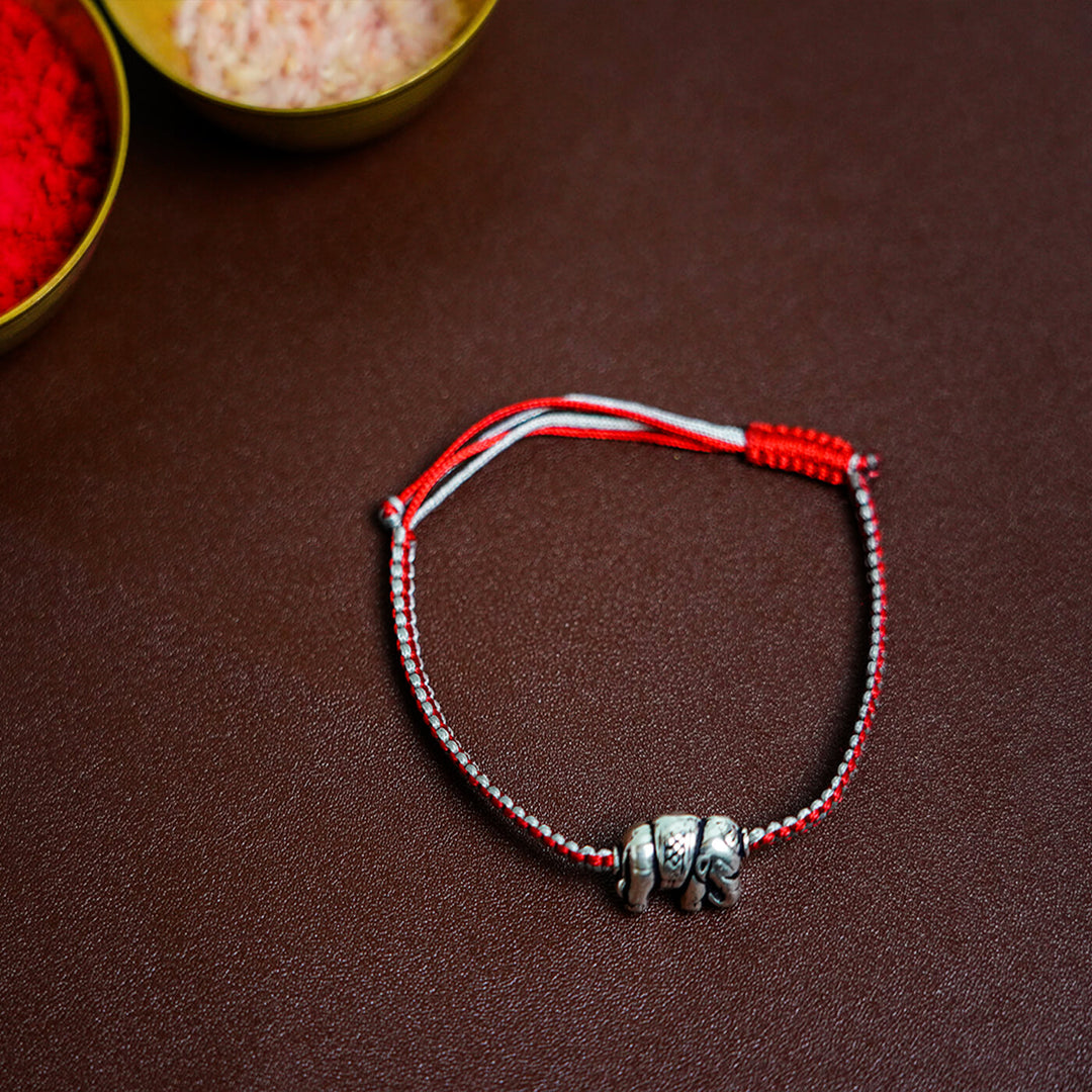 Handcrafted Silver Motif Adjustable Rakhi With Rice Roli 2 - Flat Lay Showing Knotted Pattern