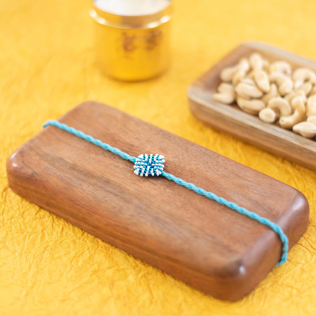 Raksha Collection Glass Beeds Rakhi Sky Blue - Styled flat lay with props